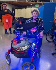 A lady smiling proudly as she shows off her newly illuminated walker with spiral light strips attached. 